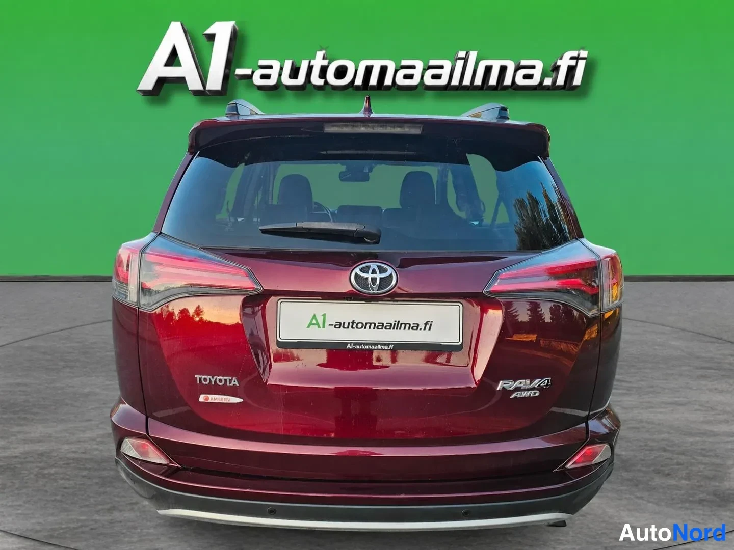 Takaa: Tummansininpunainen Toyota RAV4 suoraan takaa kuvattuna vihreää studioseinää vasten.