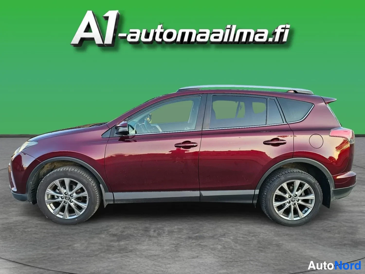 Sivulta: Sivunäkuva tummanpunaisesta Toyota RAV4 -maasturista vasemmalta, viisiovinen korimalli, hopeiset monipolttoakevanteet ja kattokaiteet näkyvät.