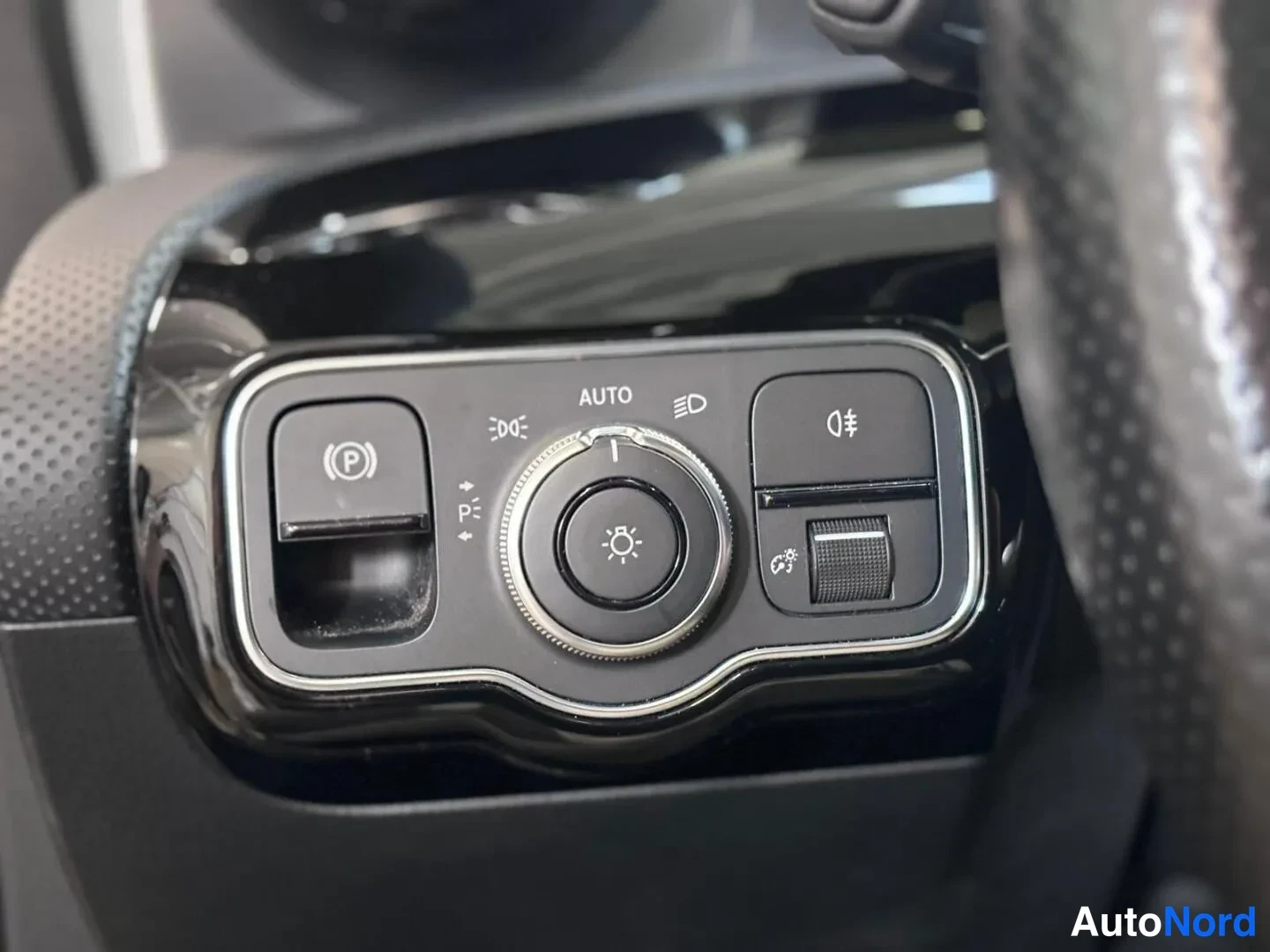 Muu: Lähikuva kojelautaan: Mercedes-Mercedes-Mercedes-Benz-valojen kytkinpainikkeet ja autoparkki.