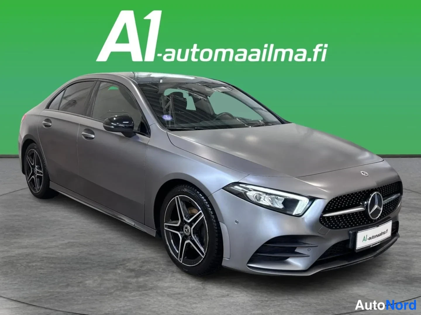 Etuviisto, nokka oikealle: Mercedes-Benz A-sarjan sedan etuviistosta oikealta, harmaa kori, mustat vanteet.