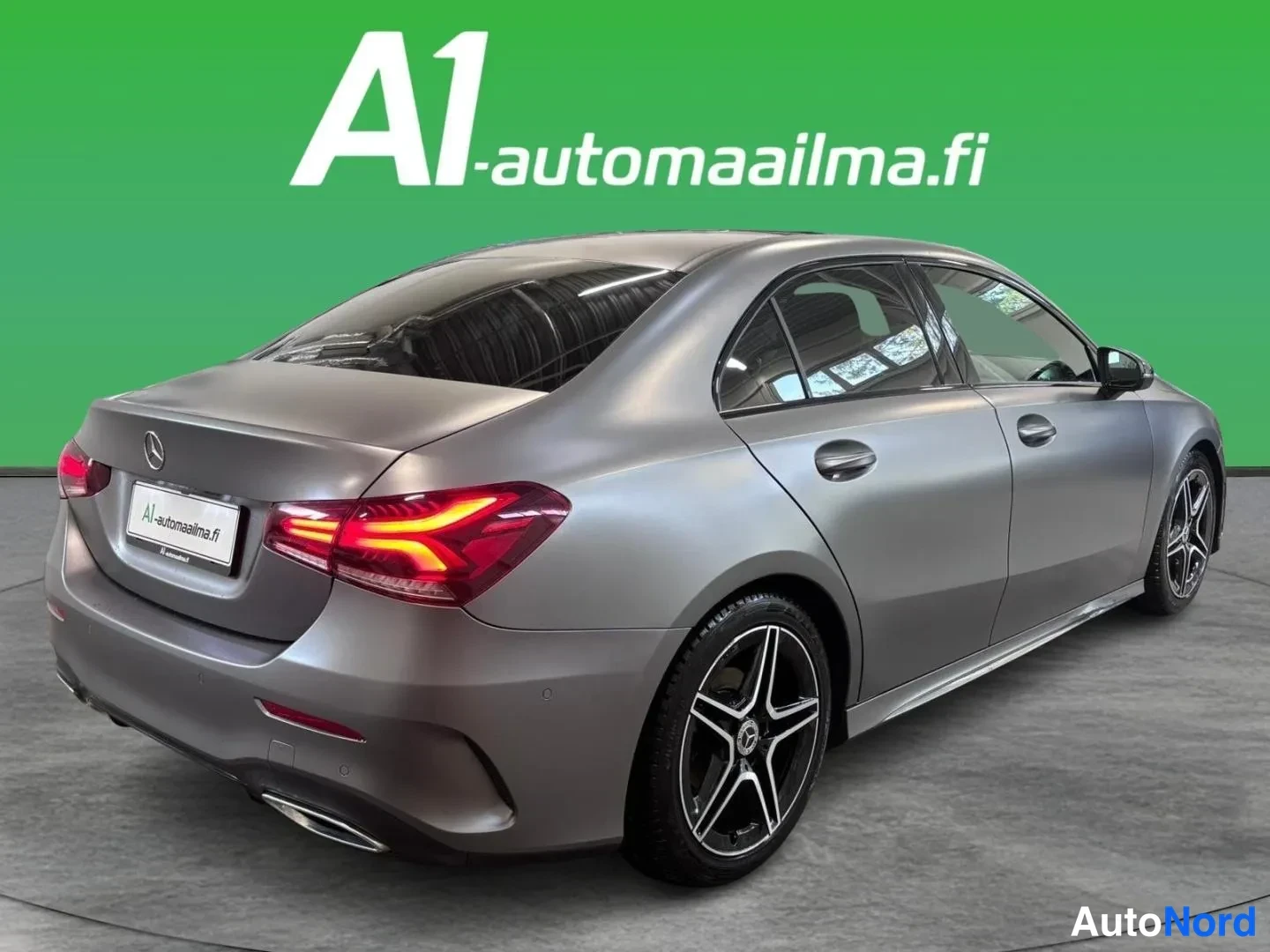 Takaviisto: Auton takaosa ja oikea kylki kolmanneskulmassa: harmaa sedan, takavalot, tummat kevytmetallivanteet ja A1-automaailma.fi-kyltti.