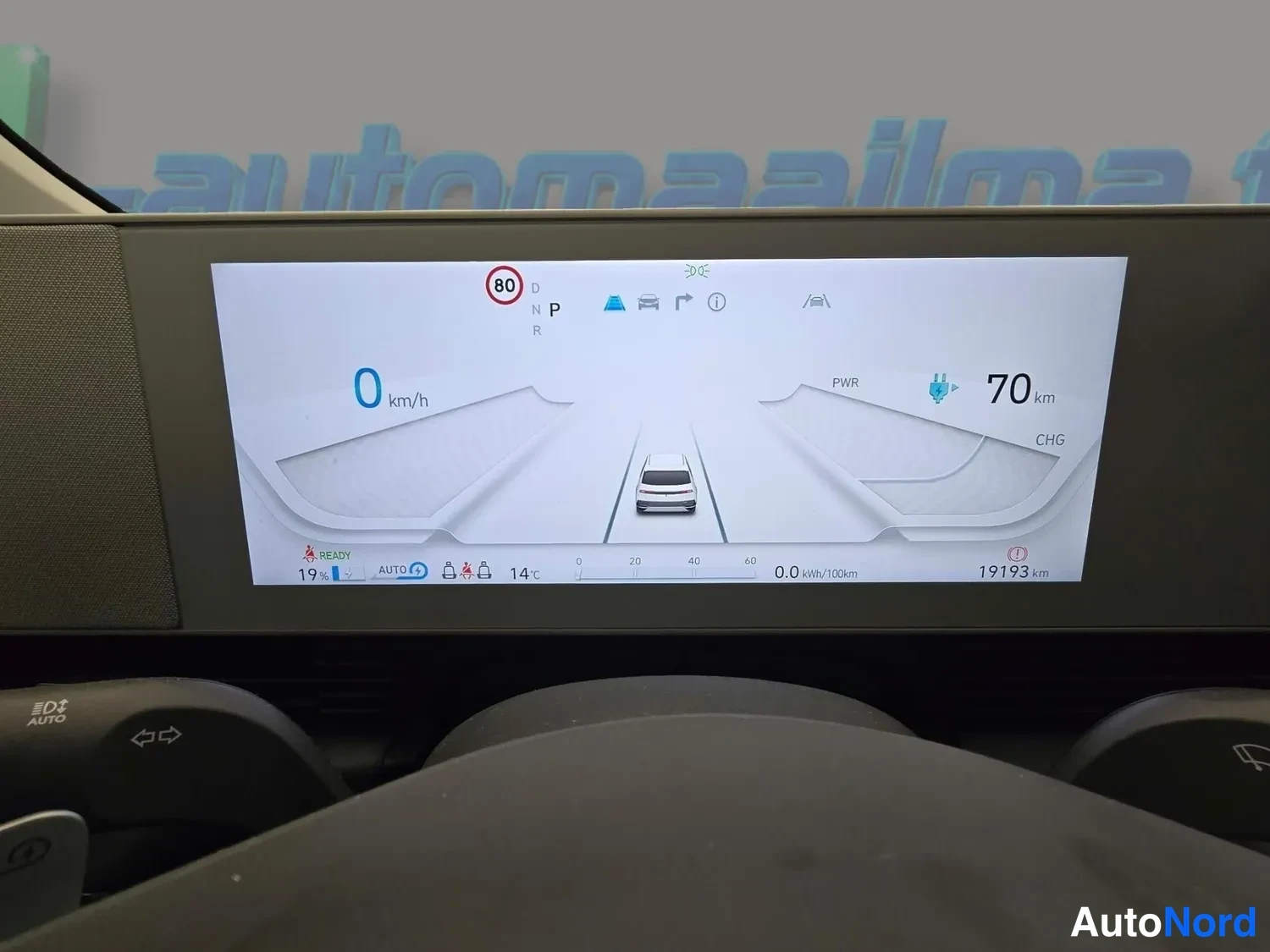Edestä: Kuljettajan näyttö näyttää 0 km/h nopeuden, vaihteen P, jäljellä 70 km, ulkolämpötilan 14 °C, akun varaustason 19 %, kulutuksen 0,0 kWh/100km ja matkamittarin 1