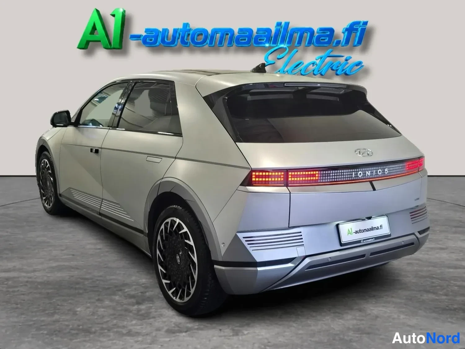 Takaviisto: Hopeanharmaa auto takaa oikealta kuvattuna, takavalot ja IONIQ 5 -teksti näkyvissä.
