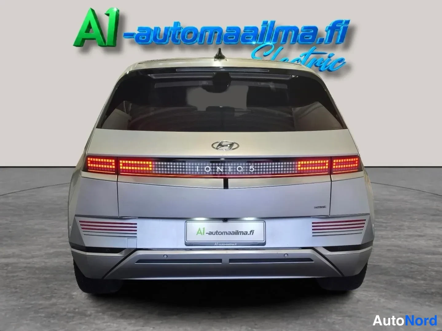Takaa: Hyundai Ioniq 5:n takaosa suoraan takaa; vaaleanhopea runko, käynnissä olevat takavalot ja IONIQ 5 -teksti