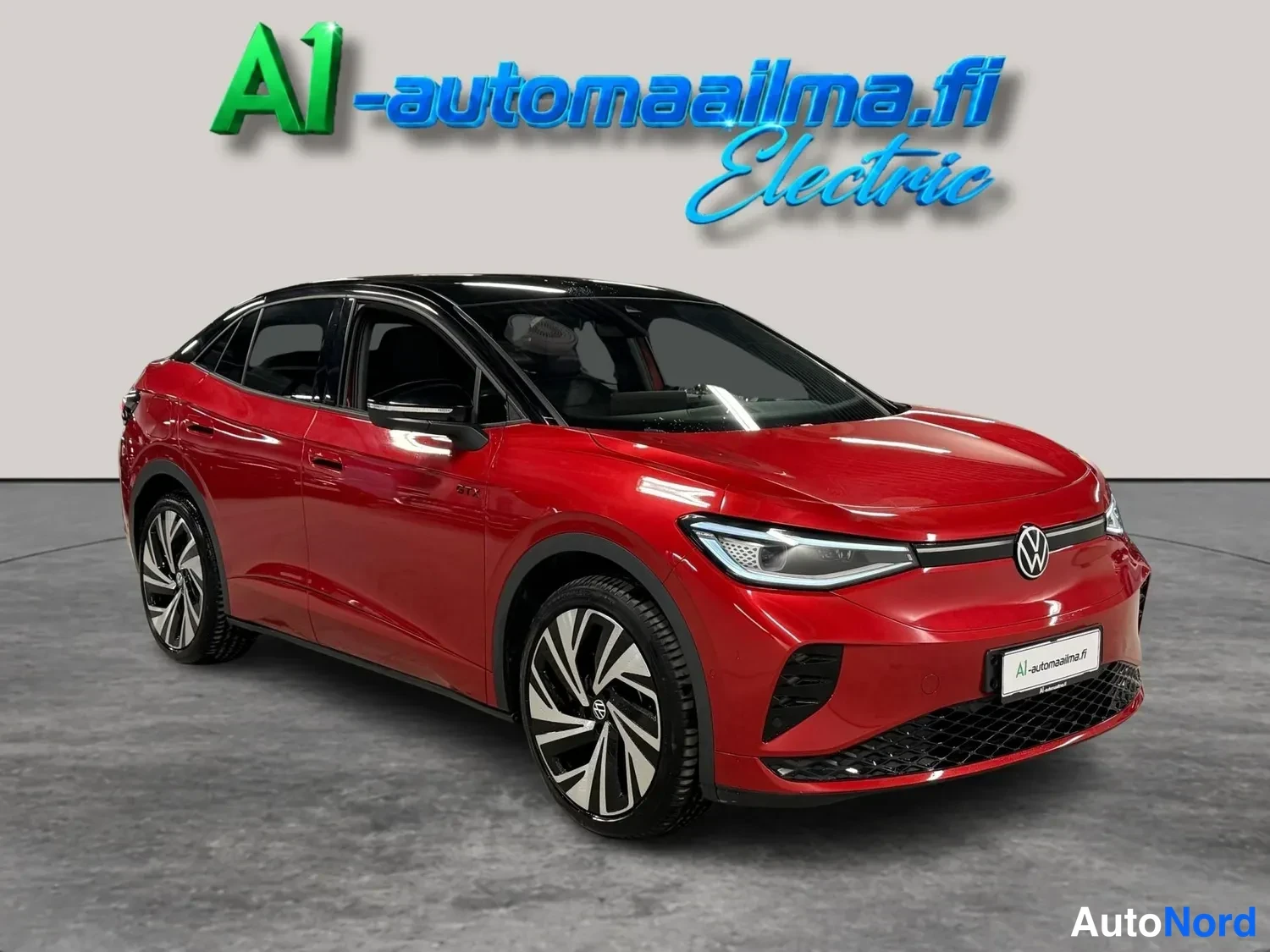 Etuviisto, nokka oikealle: Punainen Volkswagen ID.5 GTX edessä oikealta kuvattuna mustalla katolla ja suurilla kevytmetallivanteilla studioassa.
