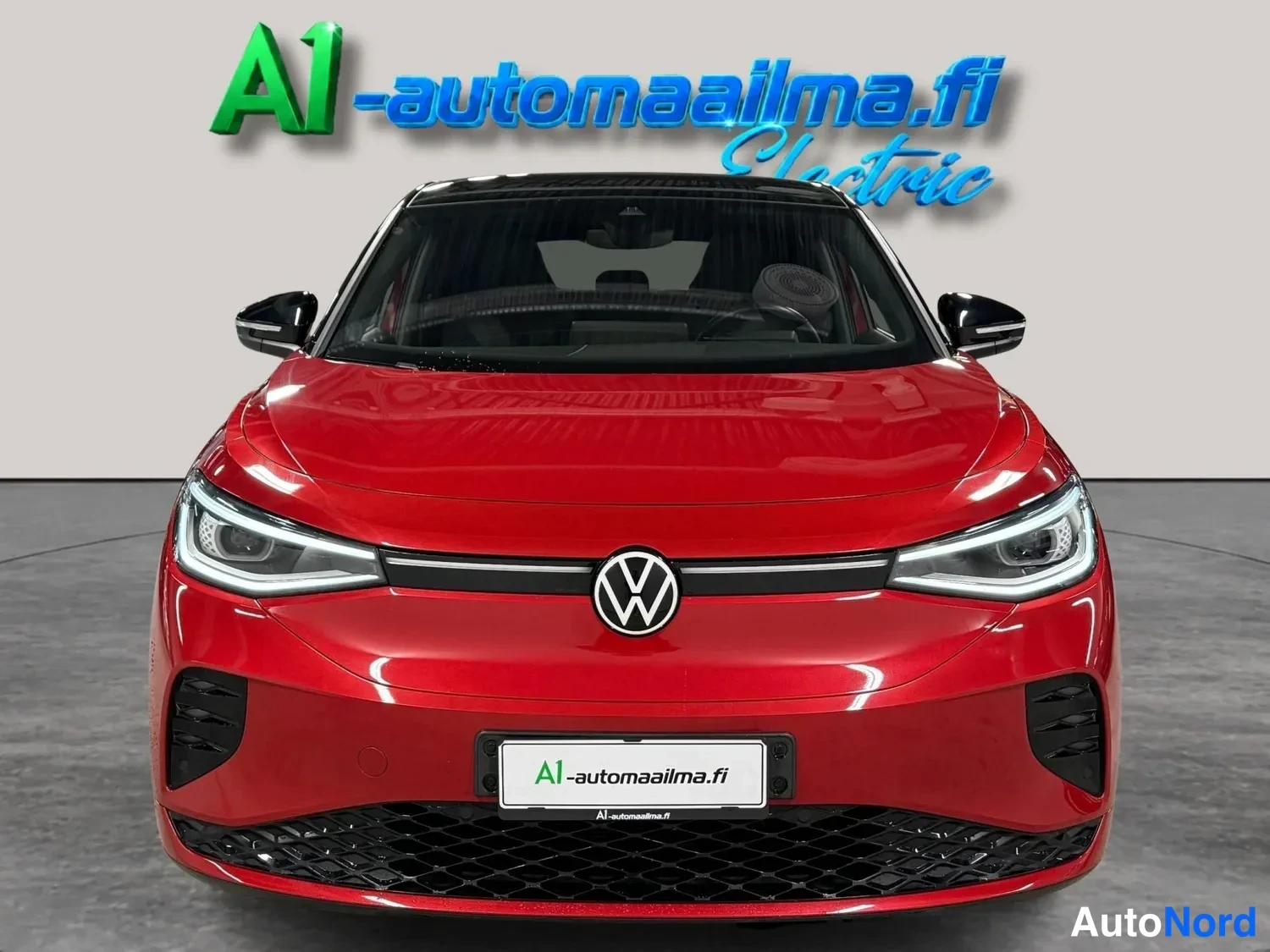 Edestä: Punaisen Volkswagenin keula suoraan edestä kuvattuna; näkyvät LED-ajovalot, keskellä oleva tunnus ja musta etuspoileri.