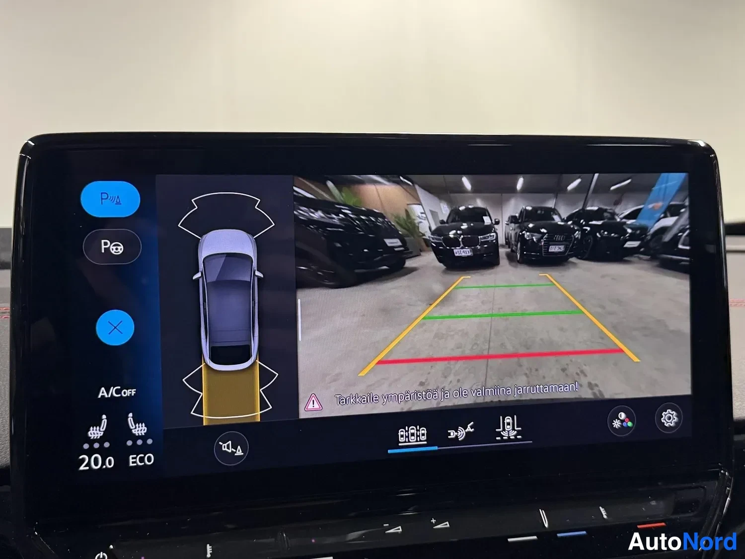 Yksityiskohta: Infotainment-näytöllä peruutuskameran kuva pysäköintitilanteesta ja pysäköintisensorien visualisointi.