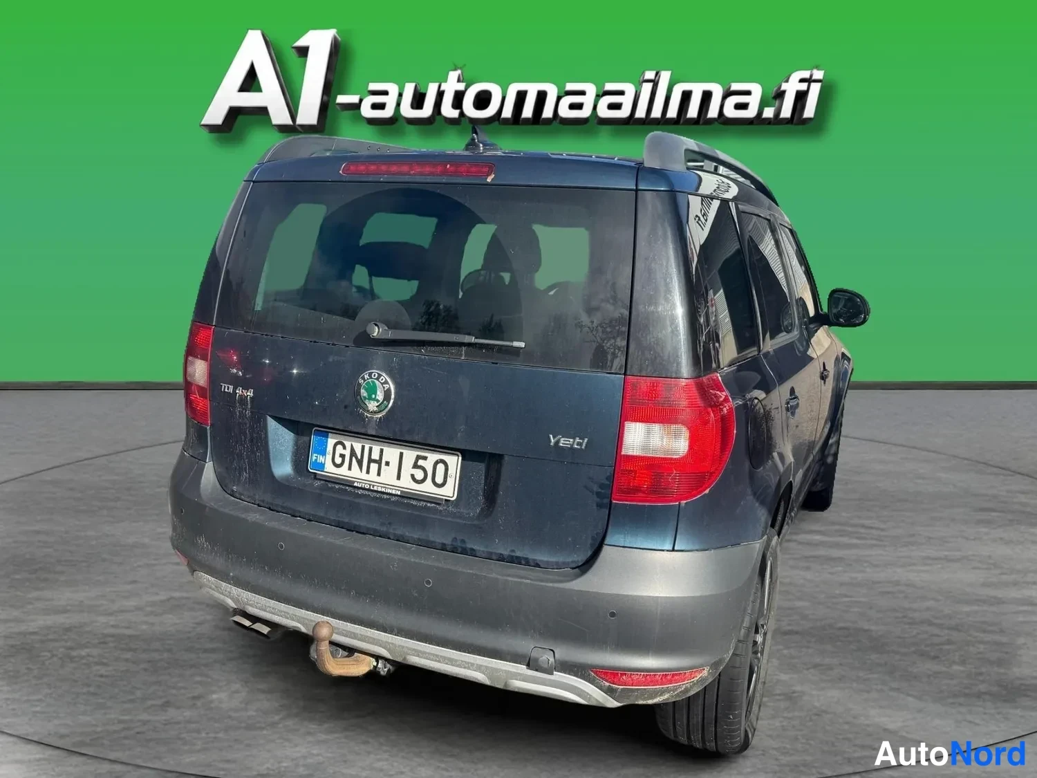 Takaviisto: Auton takaosa viistosti oikealta: tummansininen Skoda Yeti, rekisteritunnus, kattokaiteet ja vetokoukku näkyvissä, oikea kylki osittain kuvassa.