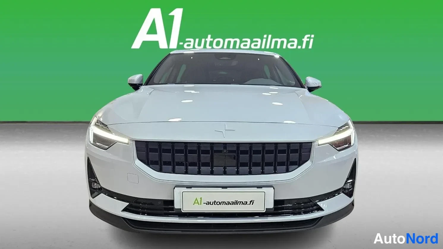 Edestä: Hopeanharmaa Polestar 2 edestäpäin, malli kuvattuna suoraan edestä vihreää taustaa vasten.
