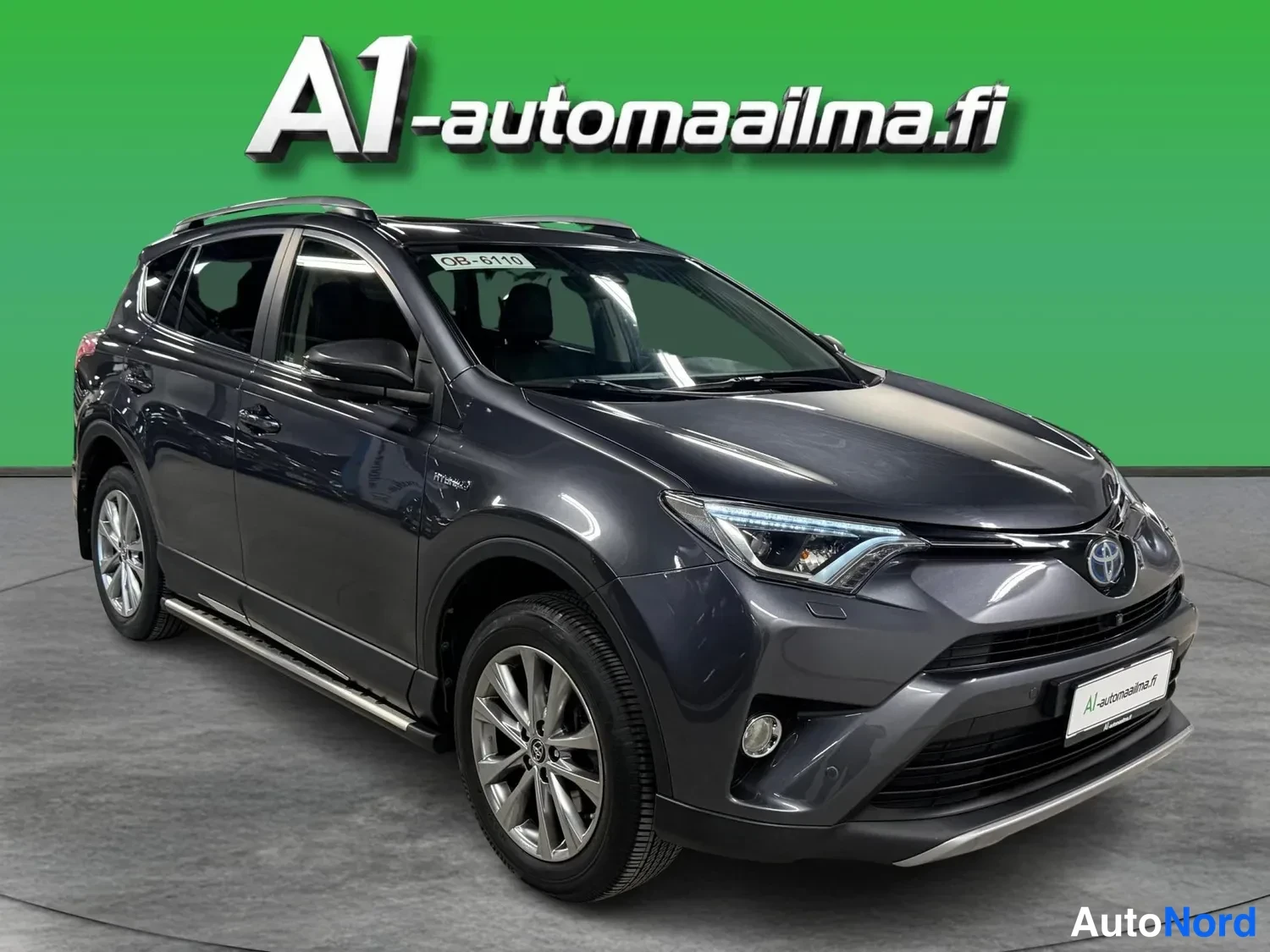 Etuviisto, nokka oikealle: Tummanharmaa Toyota RAV4 kulmassa kuvattuna, keula ja vasen sivu näkyvissä vihreällä taustalla.