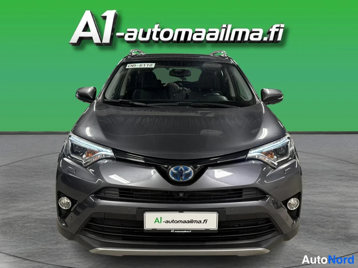 Edestä: Tummanharmaa Toyota RAV4 suoraan edestä kuvattuna, etusäleikkö ja ajovalot näkyvissä.