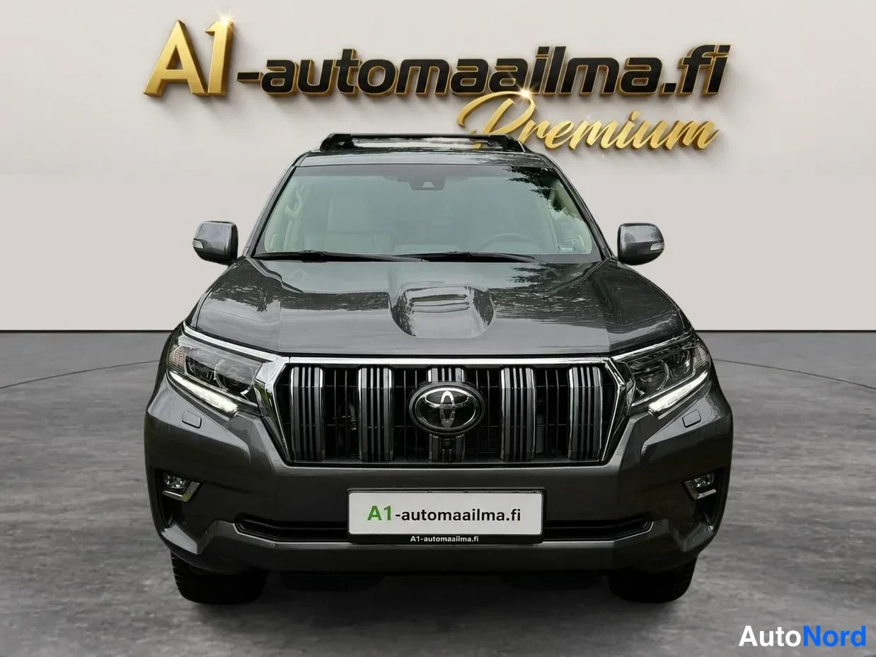 Edestä: Tummanharmaa Toyota Land Cruiser -henkinen maastopyörä suoraan edestä; Toyota-embleemi, etuvalot ja kattokaiteet näkyvissä.