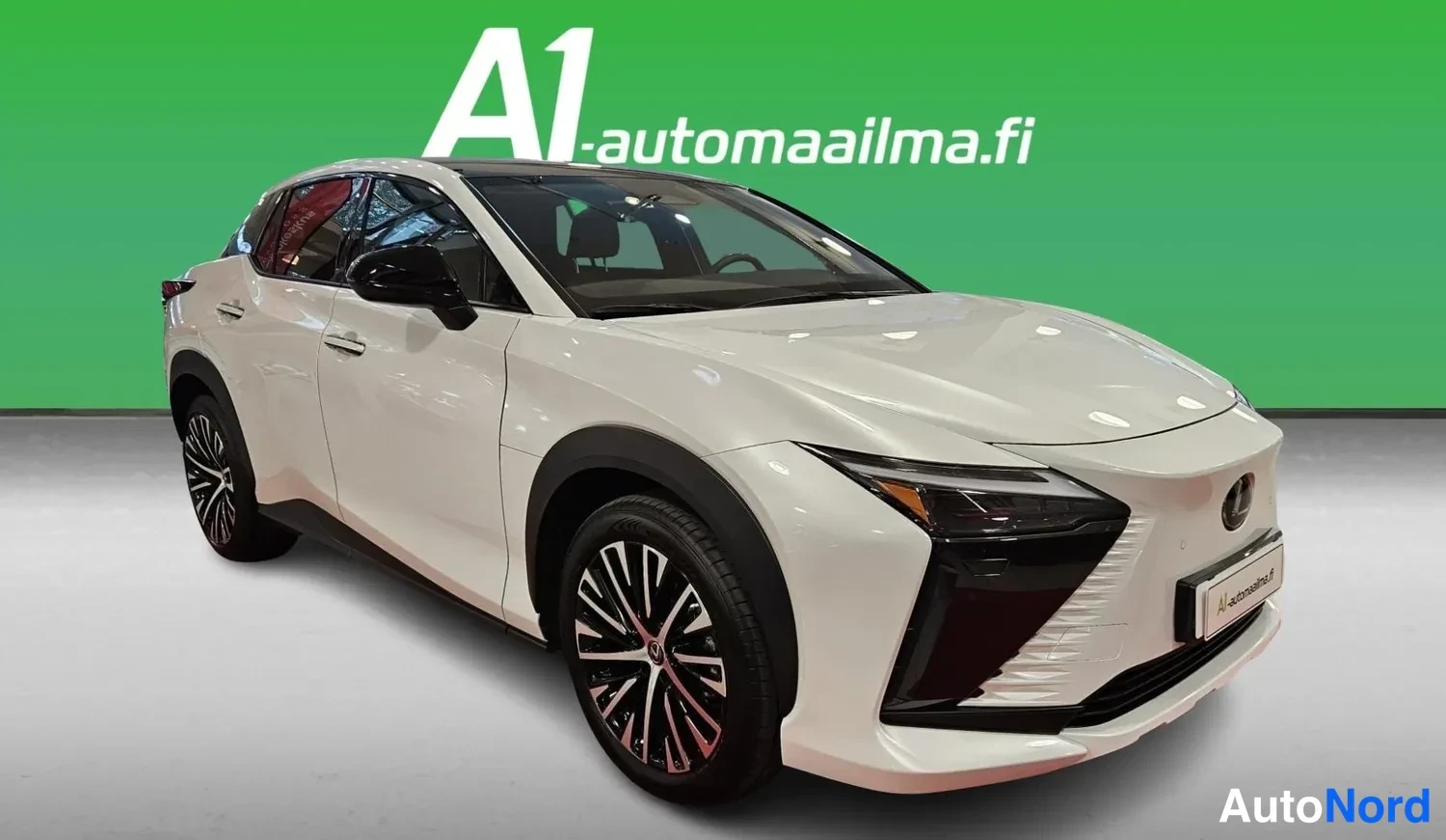 Etuviisto, nokka oikealle: White Lexus RZ photographed from a front three-quarter angle with the nose to the right, showing the grille, headlight, doors and alloy wheels in front o