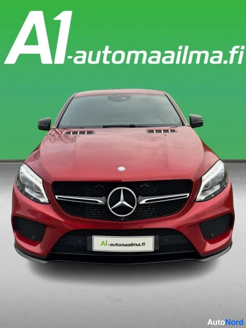 Edestä: Punainen Mercedes-Benz GLE Coupé suoraan edestä vihreää taustaa vasten; etusäleikkö ja ajovalot näkyvät selvästi.