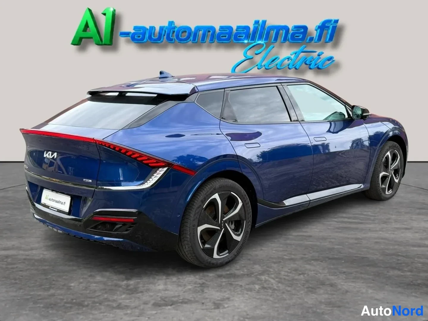 Takaviisto: Sininen Kia EV6 takaviistosta kuvattuna; tumma kylkivara, moniosaiset kevytmetallivanteet ja jatkuva takavalo.