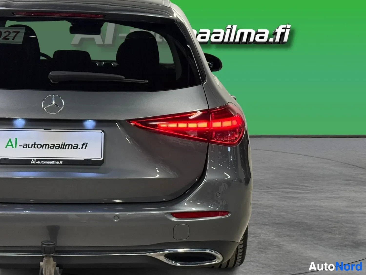 Takaa: Lähikuva auton takaosasta: Mercedes-tähti, takavalot, perävaunukoukku ja puskurin anturit.