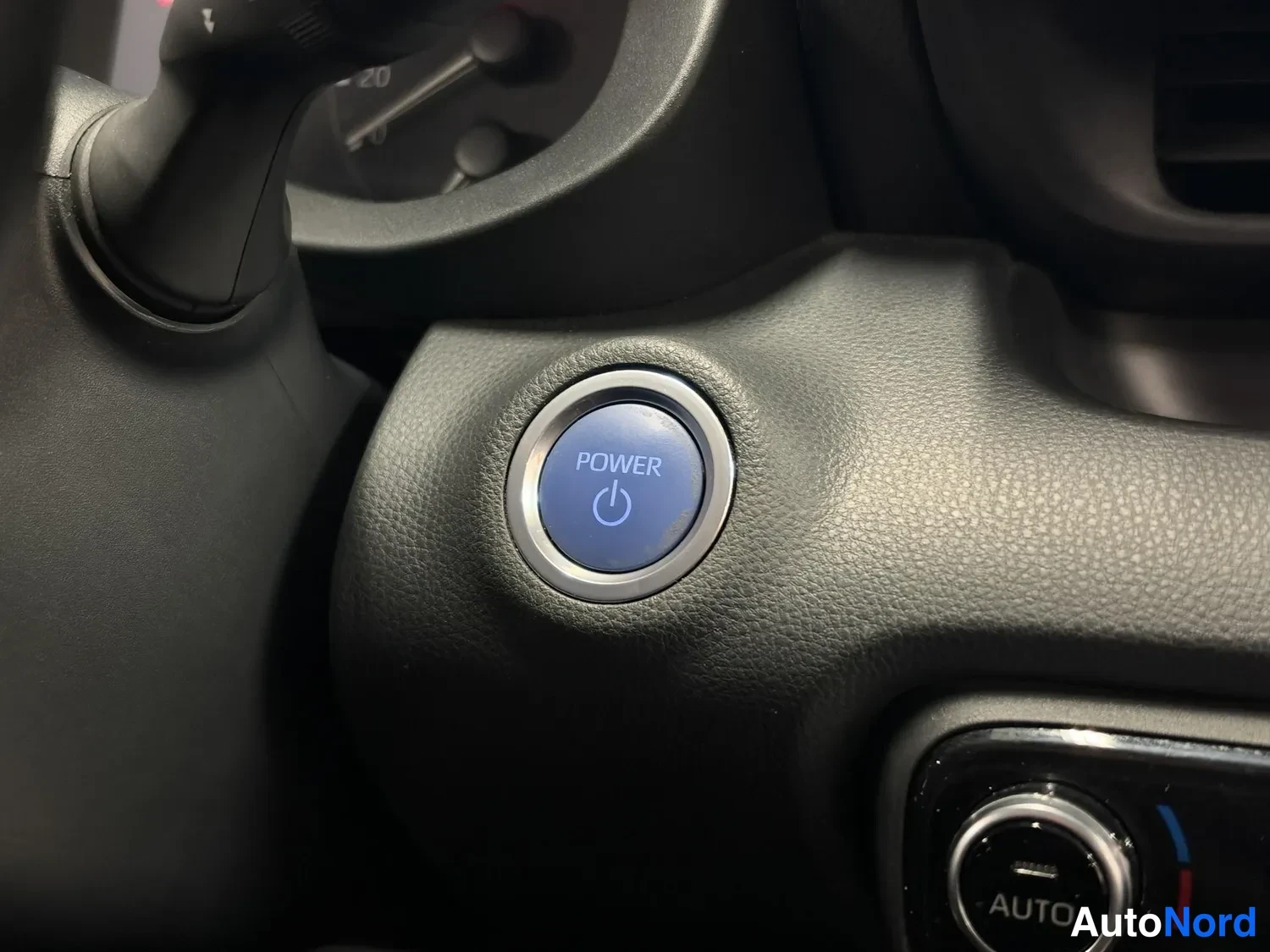 Muu: Sininen POWER-käynnistyspainike kojelaudassa, vieressä näkyy AUTO-ilmastointipainike.