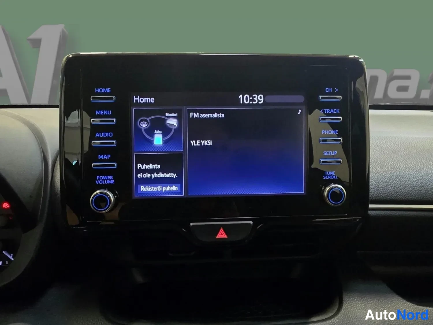Muu: Koskettava infotainment-näyttö, kello 10:39, FM-asemalista YLE YKSI, teksti 'Puhelinta ei ole yhdistetty', Rekiateröi puhelin -painike ja Home-, Menu-, Audio-,