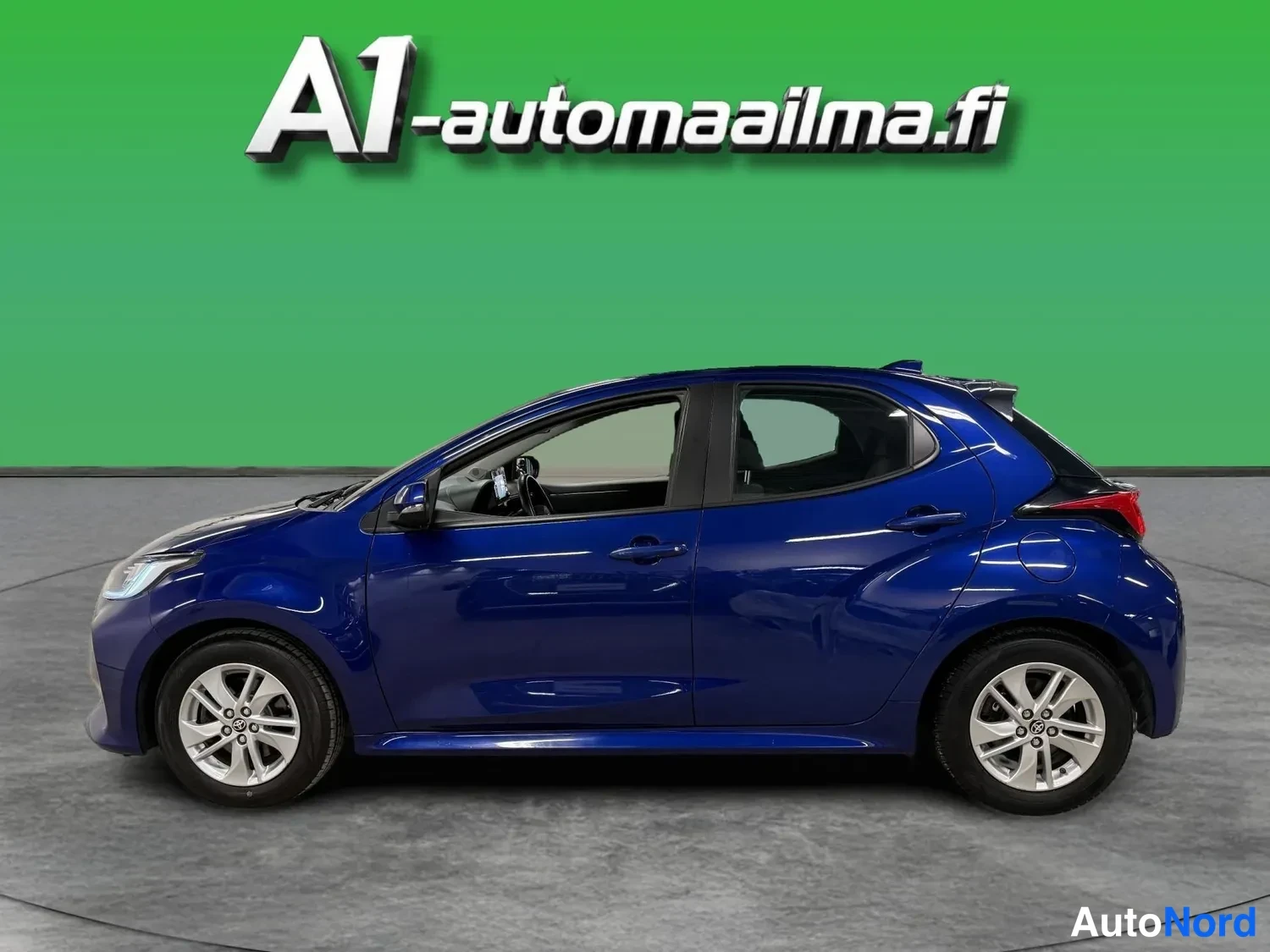 Etuviisto, nokka vasemmalle: Sininen Toyota Yaris -henkinen viistosti edestä vasemmalta kuvattu viistoprofiili studiovihreällä taustalla.