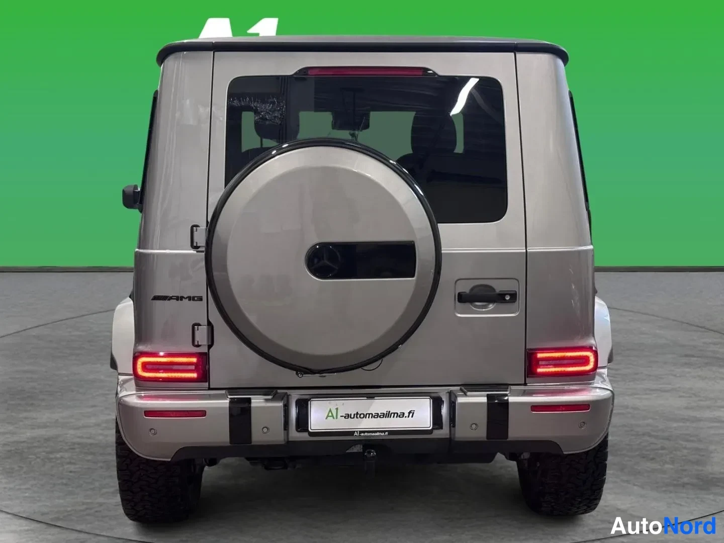 Takaa: Mercedes-Benz G -luokan suora takanäkymä, varapyörä takaluukussa, AMG-teksti ja punaiset takavalot.