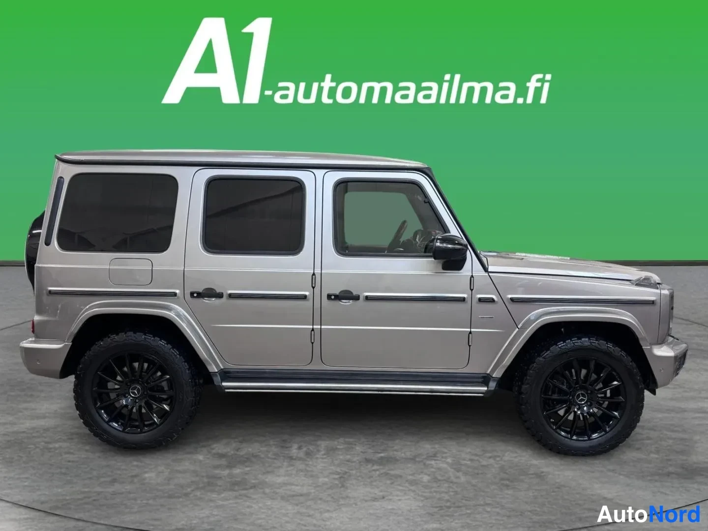 Sivulta: Sivukuva beigestä Mercedes-Benz G-luokan maasturista, jossa mustat kevytmetallivanteet ja tummat ikkunat.