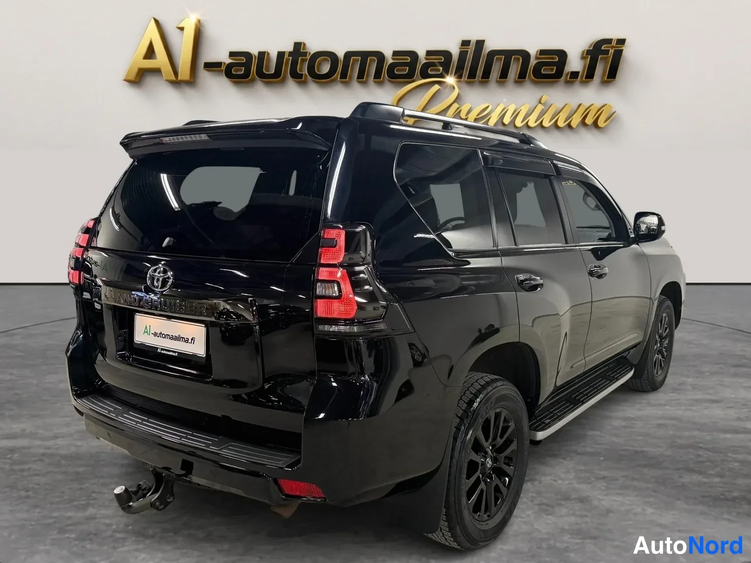 Takaviisto: Musta Toyota Land Cruiser kulmasta takaa vasemmalta kuvattuna, kylki ja takapää näkyvissä.