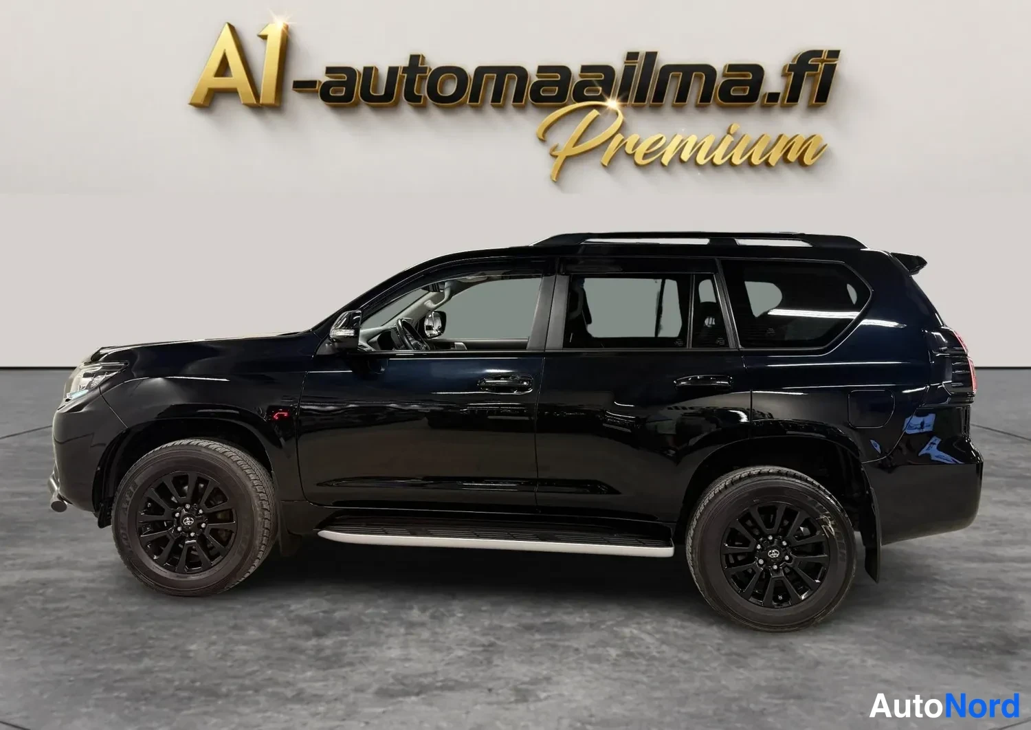 Sivulta: Mustan Toyota Land Cruiserin sivunäkyväs koko auto vasemmalta, tummat kevytmetallivanteet ja sivulaidat.