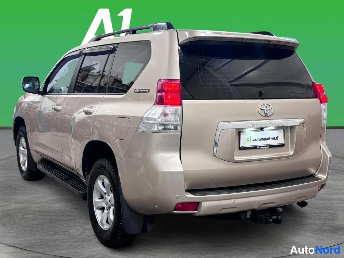 Takaviisto: Beige Toyota Land Cruiser takakolmivartalokulmasta oikealta, peräosa, takavalot ja molemmat sivut näkyvät studiopohjalla.