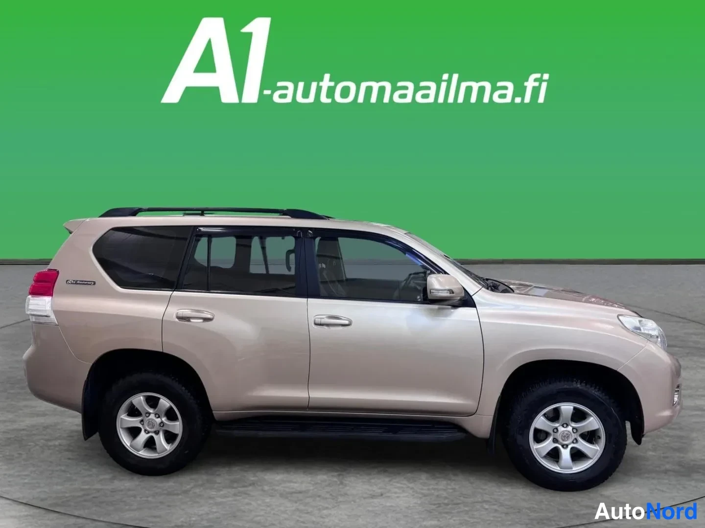 Etuviisto, nokka oikealle: Beige-kultainen Toyota Land Cruiser kulmittain etusivu oikealta: kylki ja keulä näkyvissä, kattokaiteet, ovensivat ja sivulaittapalkit kuvattuna vihreäll