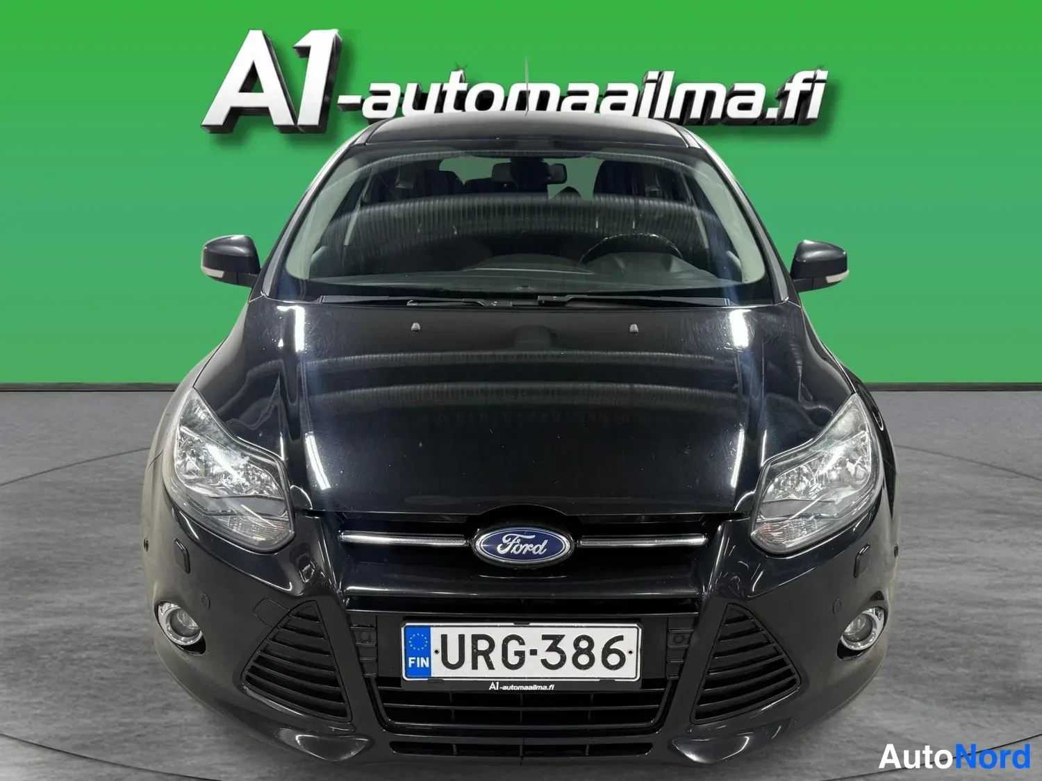 Edestä: Musta Ford Focus -asema-auto suoraan edestä, rekisterimerkki.
