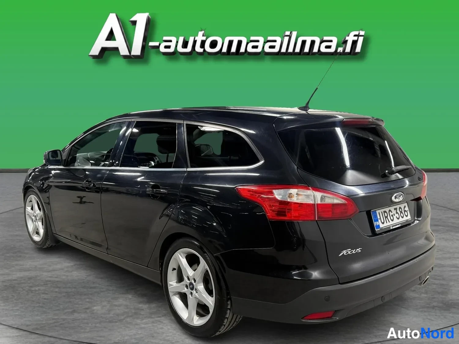 Takaviisto: Ford Focus -farmari takaviistokuva vasemmalta: musta koripaneeli ja lumivaatteet, Ford-merkki ja Focus-teksti luistiluukun alareunassa, rekisteritunnus, hopeise