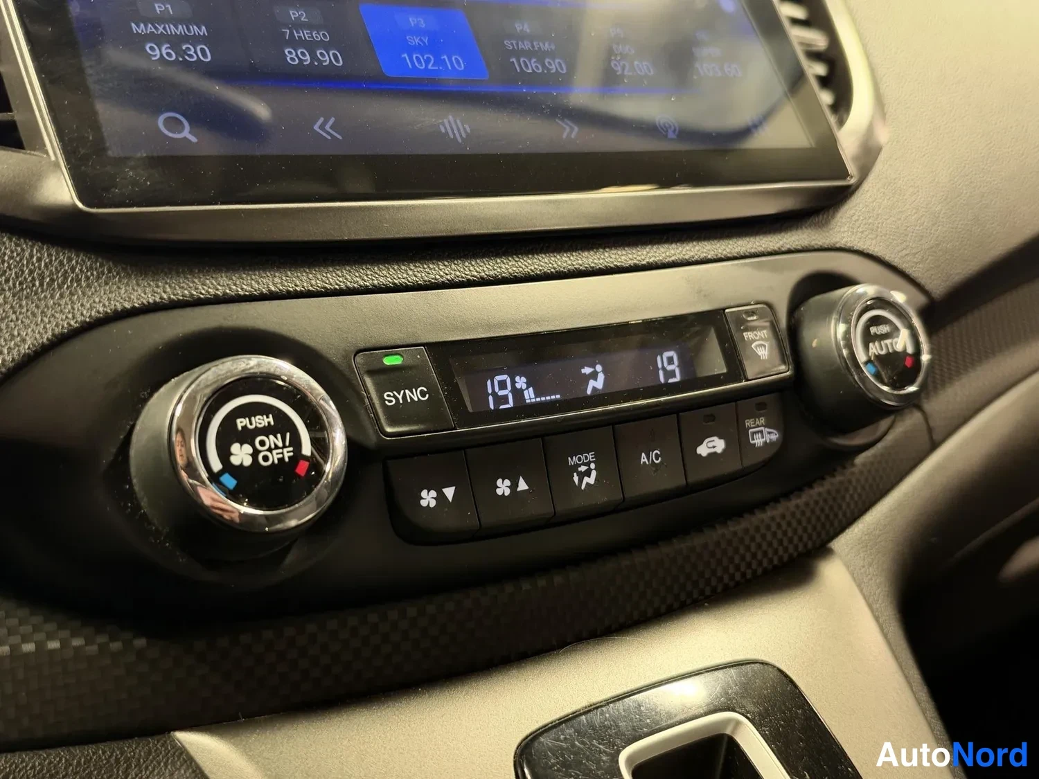 Muu: Lähikuva automatiikan ilmastointipaneelista: näytössä 19 astetta, painikkeet SYNC, A/C, PUSH ON/OFF ja PUSH AUTO