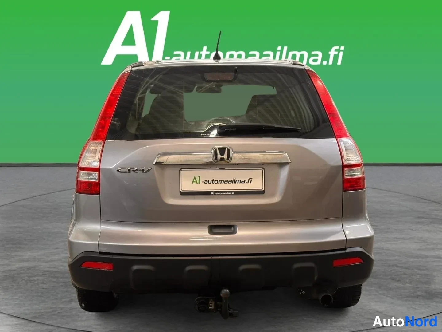 Takaa: Honda CR-V:n takaosa suoraan takaa; hopeanharmaa kori, nested taka- ja jarruvalot, Honda-merkki, CR-V-teksti ja takavakokoukku.