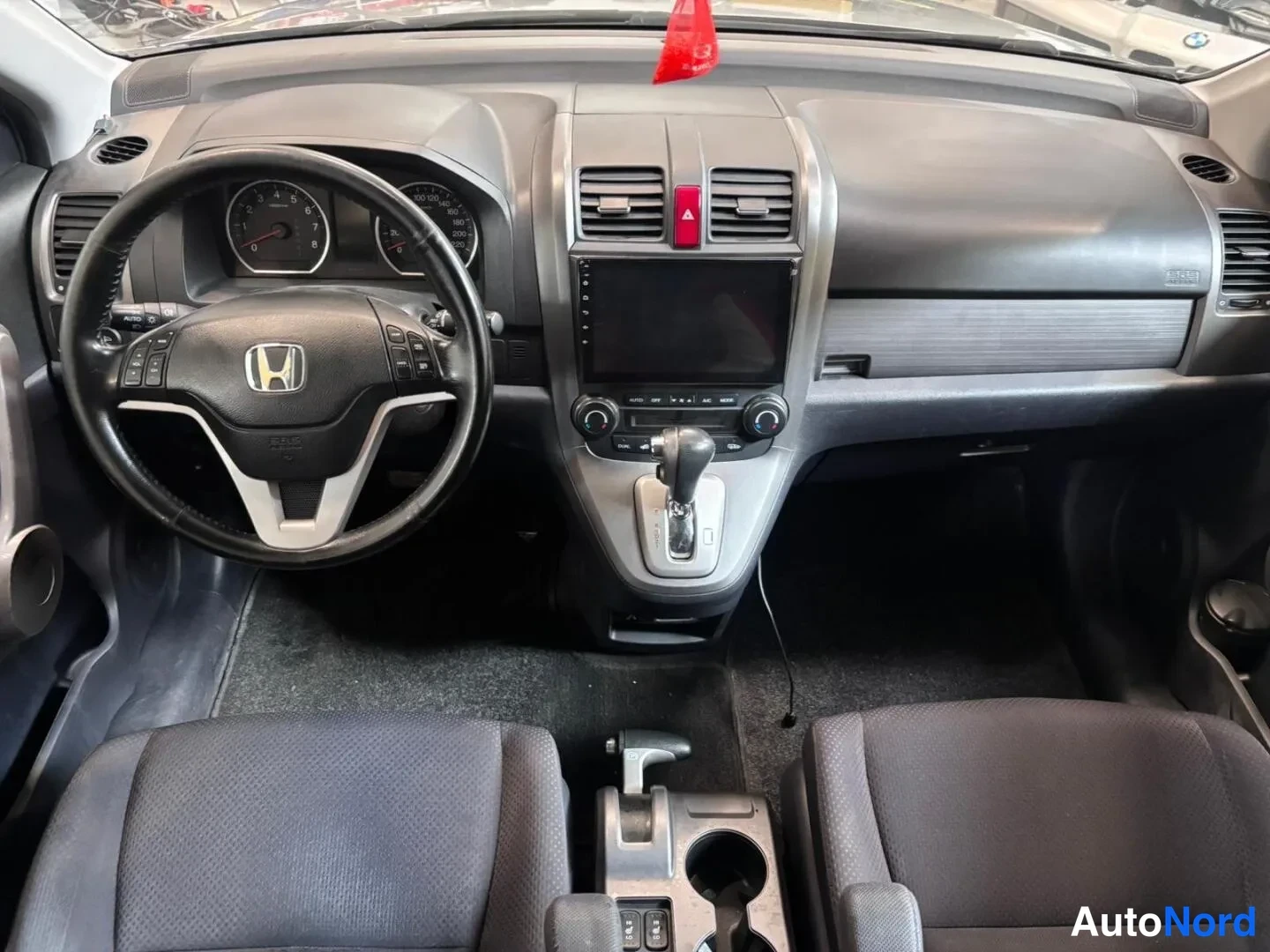 Muu: Honda CR-V:n ohjaamo etuistuimilta kuvattuna: Honda-merkkinen ohjauspyörä, mittaristo, kosketusnäyttö keskikonsolissa, automaattivaihteen valitsin ja tummat kan