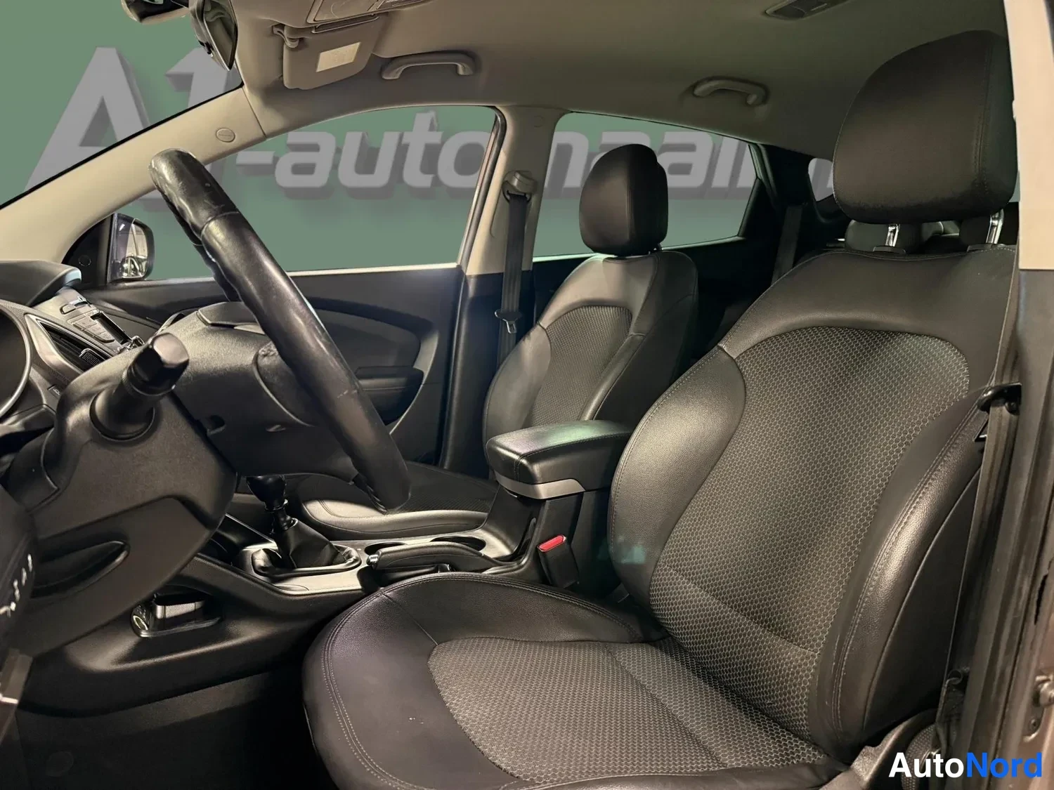 Muu: Hyundai ix35:n etusohva ohjaamosta: kaksi tummaa nahkapintaverhoiltua penkkiä ja keskikäytävä.