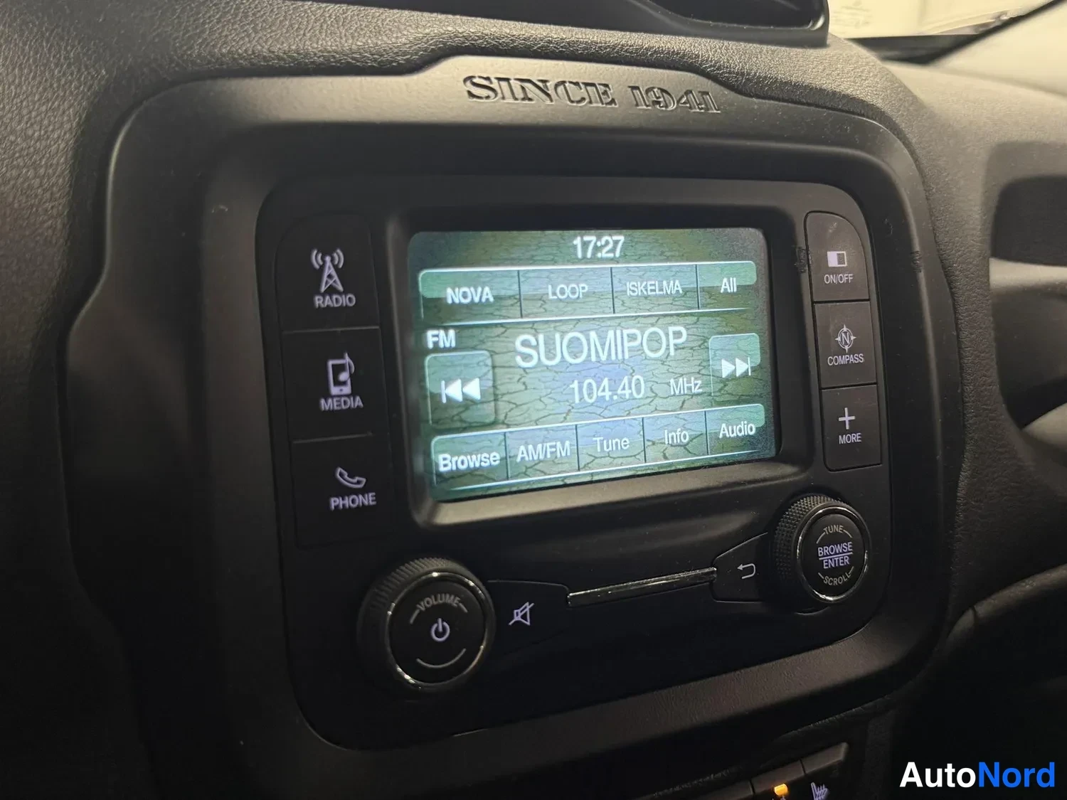 Yksityiskohta: Auton radionäyttö, jossa kuunnellaan Suomipop FM-kanavaa taajuudella 104.40 MHz; paneelissa RADIO-, MEDIA- ja PHONE-painikkeet.