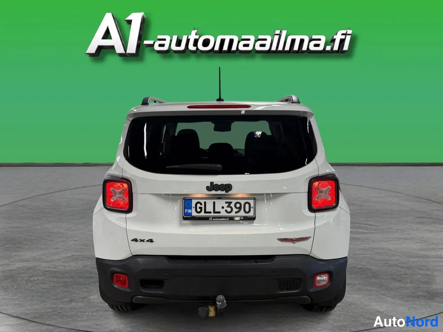 Takaa: Valkoinen Jeep Renegade takaa nähtynä, rekisteritunnus, punaiset takavalot, kiinnikkeessä oleva kytkinlaakeri ja 4x4-merkintä.