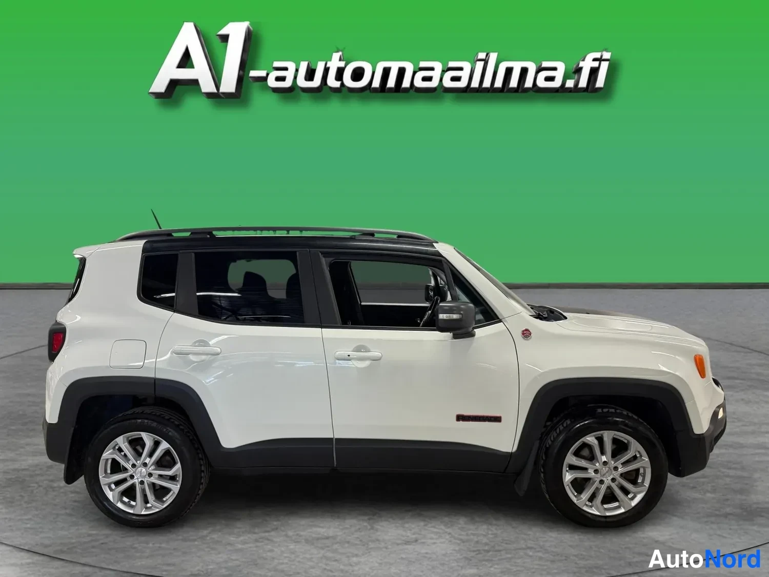 Sivulta: Valkoinen Jeep Renegade kyljestä nähtynä, tummat kynnykset, hopeiset vanteet ja tumma katotunnus.