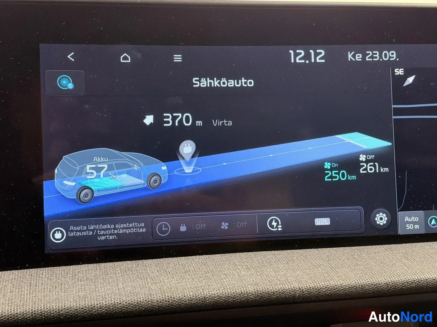 Yksityiskohta: Istuttokuvan infotainment-näyttö sähköauton näkymässä: akun varaustaso 57 %, 250 km toimintamatka, 261 km laskennallinen toimintamatka sekä 370 m matka latauspi