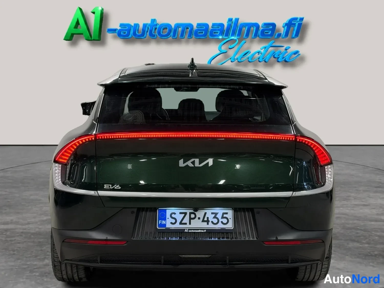 Takaa: Kia EV6:n takaosa suoraan takaa; vaaleanvihreä kylki, punainen KIA-logon valaistu takavalotanko ja rekisteri.