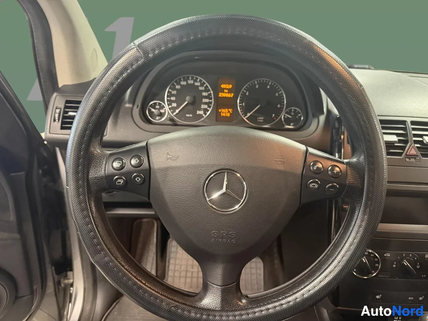 Muu: Ratti lähikuvaan: Mercedes-tunnuksella varustettu ohjauspyörä, SRS Airbag -merkintä ja nappeja molemmin puolin; mittaristossa näkyy lukema 228667 km.