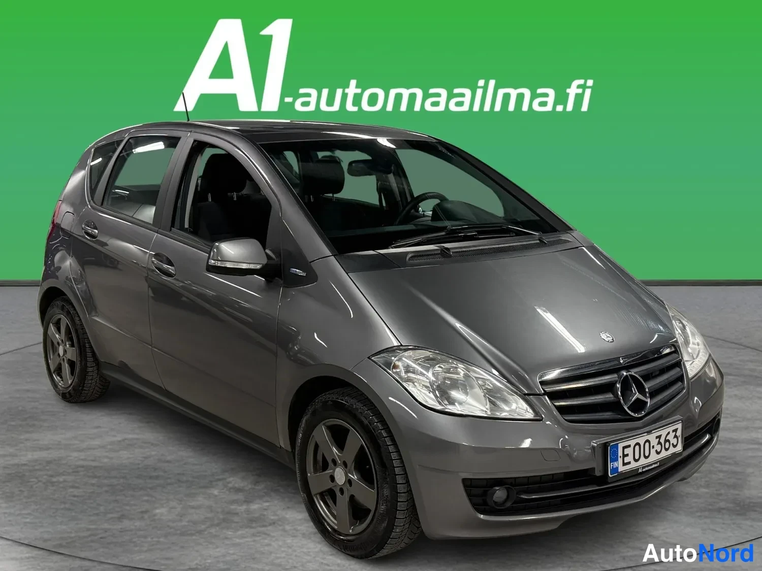 Etuviisto, nokka oikealle: Harmaa Mercedes-Benz A -sarja viistoperä etuosa oikealta kuvattuna, rekisterikilpi E00-363.