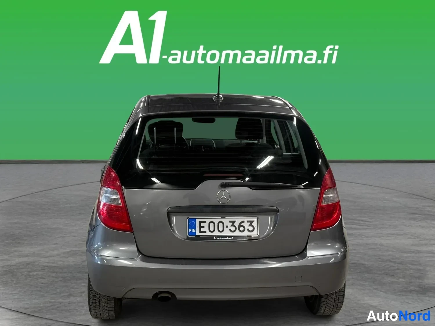 Takaa: Mercedes-Benz A-sarjan hatchbackin takaosa eteenpäin: harmaa kori, rekisterikilpi E00-363, takaovat ja Mercedes-tähti luukussa.