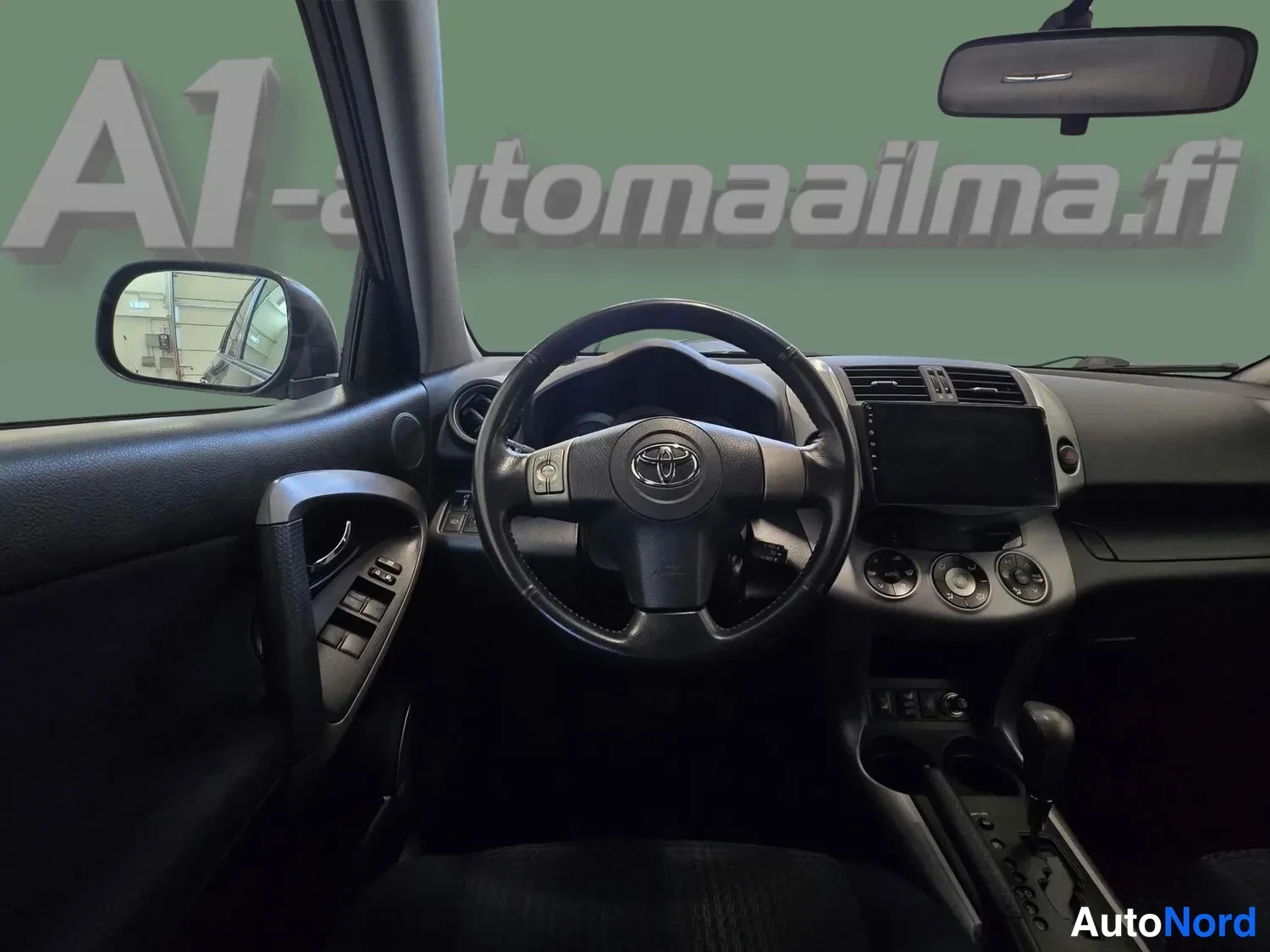 Yksityiskohta: Ohjaamon yleiskuva, ratin Toyota-logo, tumma sisusta