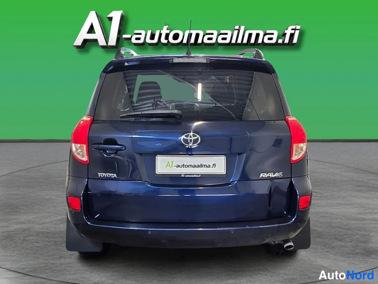 Takaa: Sinisen Toyota RAV4:n takaosa suoraan takaa: takavalot, nokakansi Toyota- ja RAV4-embleemeillä, takalasi ja pyyhin.