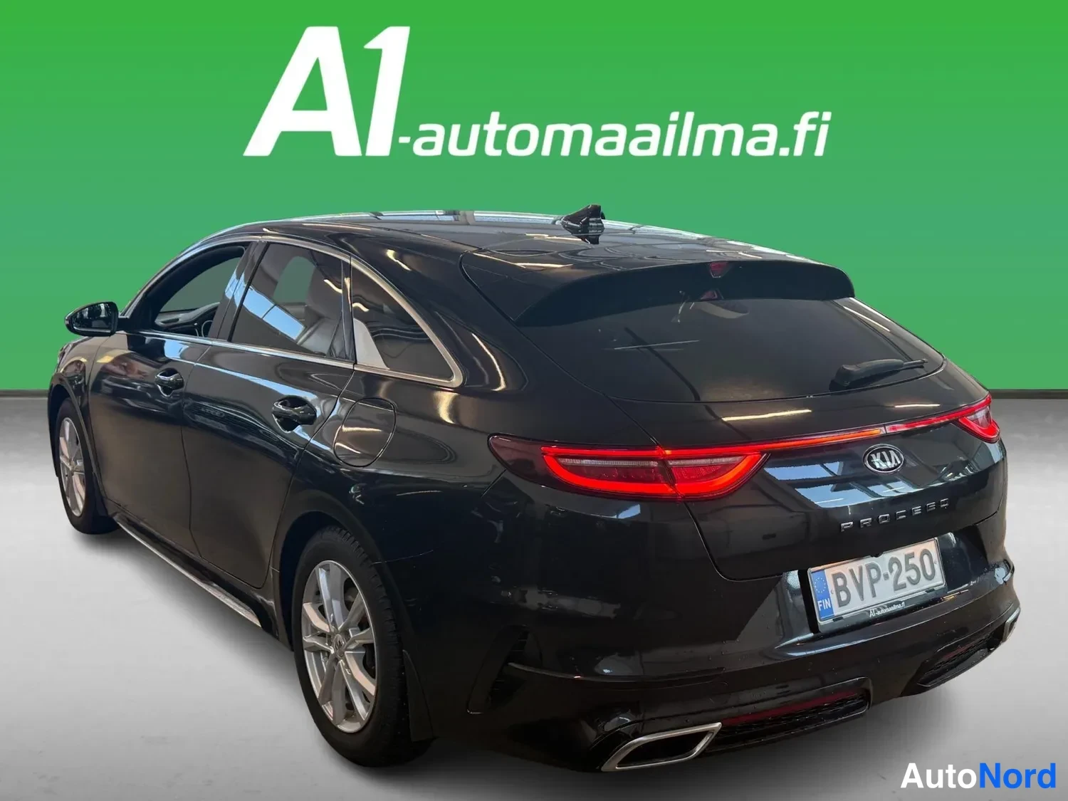 Takaviisto: Mustan Kia ProCeedin takaa kolmannesvasemmalta kuvattu: vasen kylki, takavalot, rekisterikilpi ja hopeavanteet.