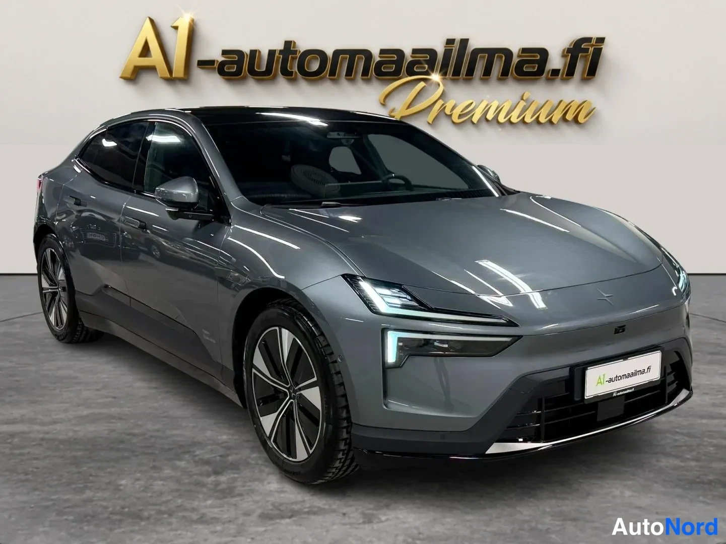 Etuviisto, nokka oikealle: Harmaa sähköauto etuosalta kolmanneksesta kuvattuna sisätiloissa.