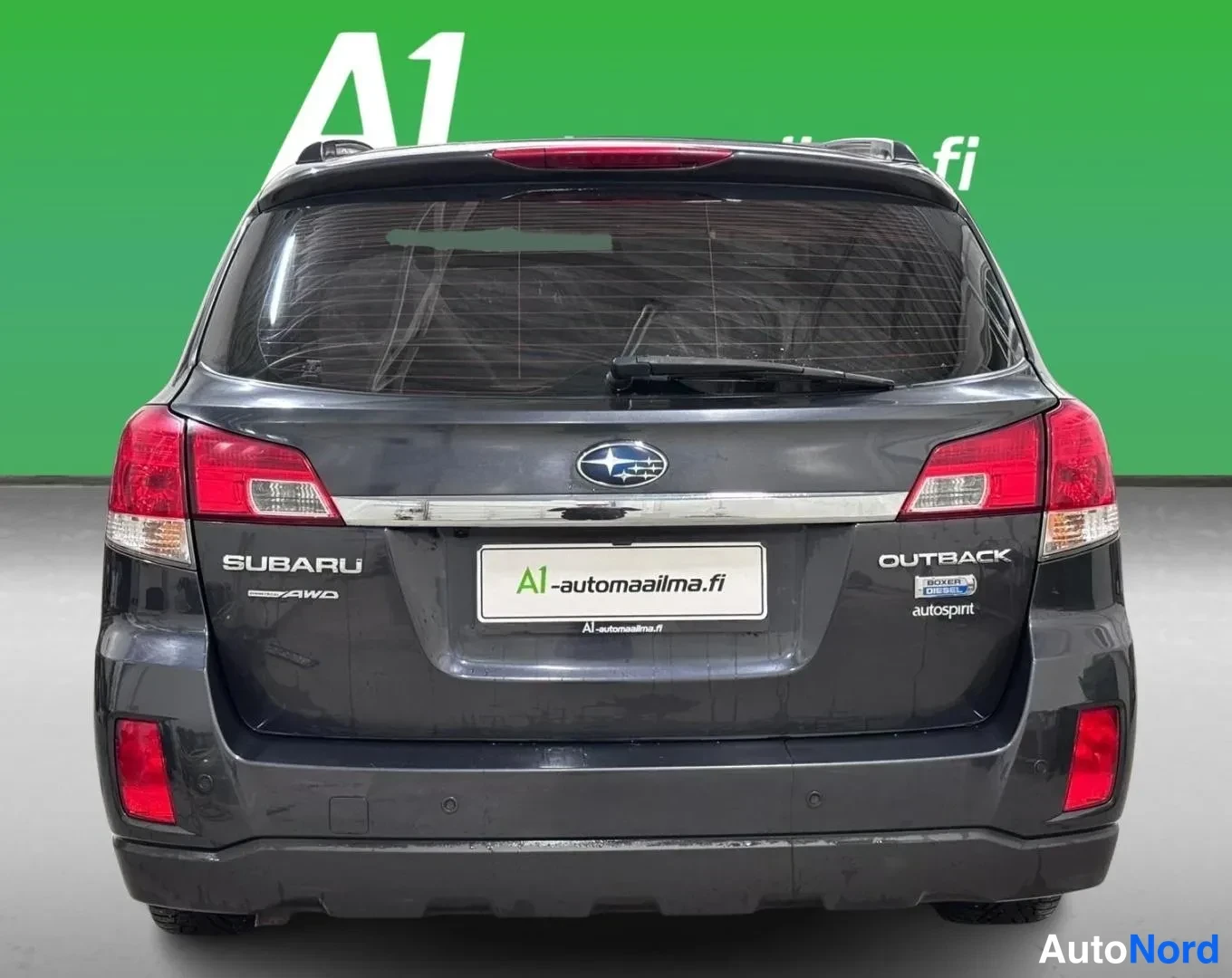 Takaa: Tummanharmaa Subaru Outback suoraan takaa kuvattuna; SUBARU-, AWD- ja OUTBACK-merkinnät sekä takapuskurin anturit näkyvät.