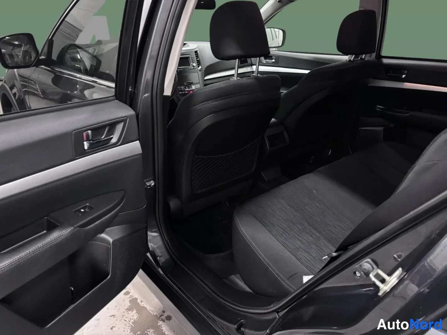 Muu: Takaistuimen ja avatun etuoven sisäpinnan näkymä; musta kankaanverhoilu ja etumatkustajan oven sisäosa.