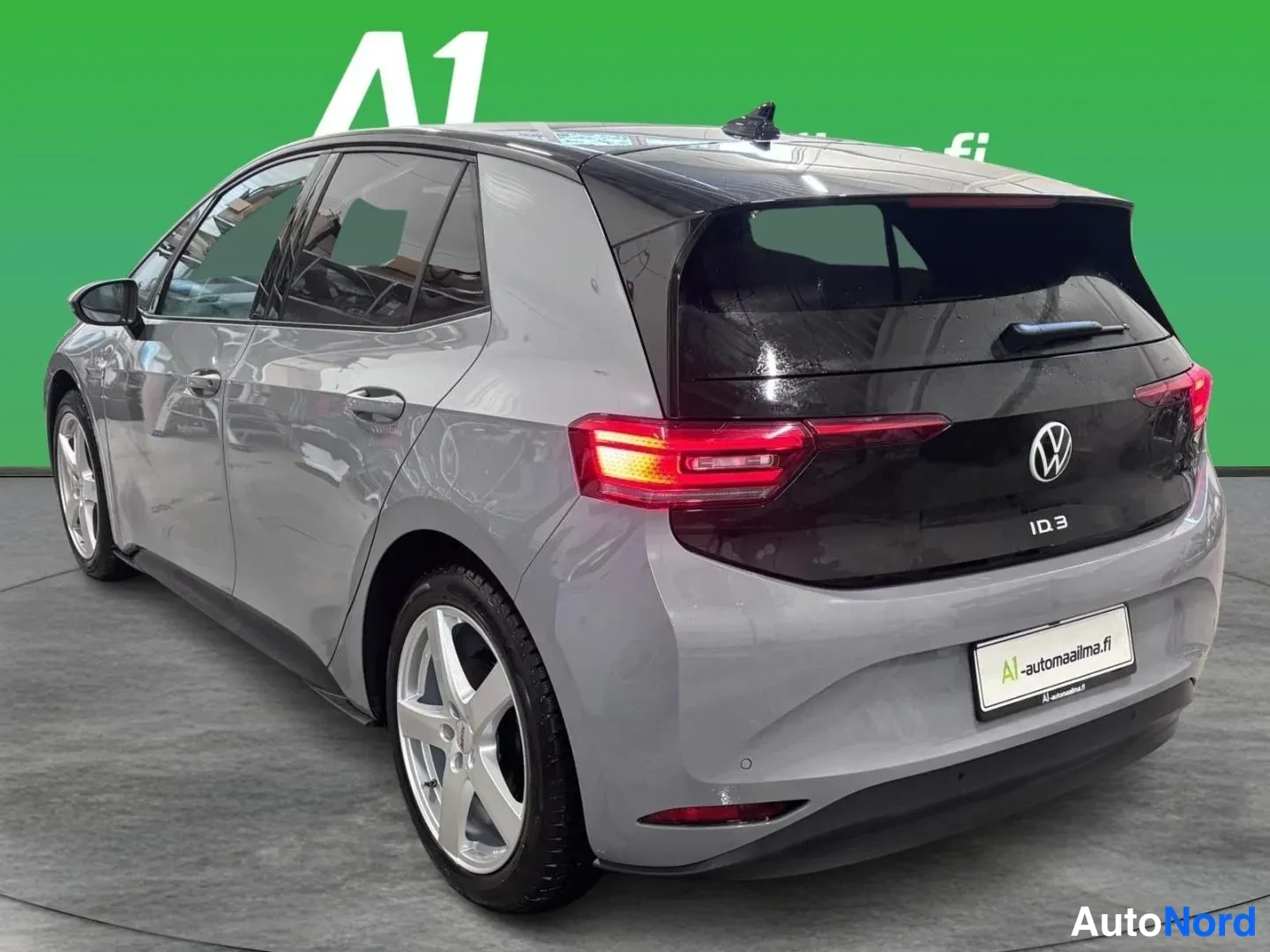 Takaviisto: Auton takaosa ja vasen sivu näkyvät: tummat takavalot, Volkswagen-merkki ja ID.3-teksti, harmaa koripinta.